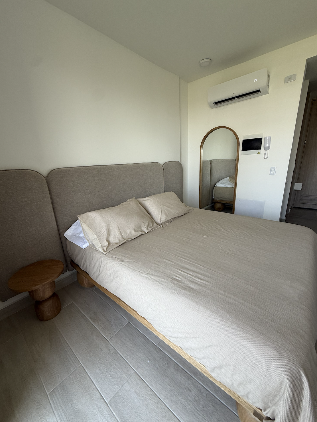 Cama queen con mesa lateral y espejo en la suite
