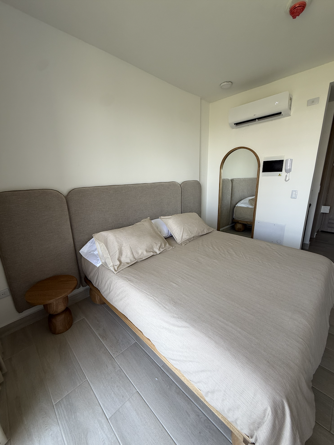 Habitación principal con cabecero tapizado y espejo de cuerpo entero
